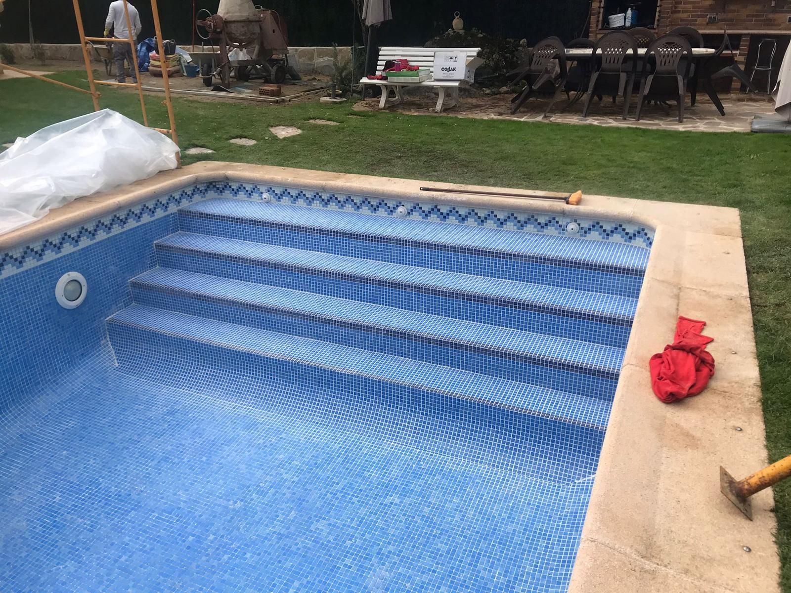 Detalle de escalera de piscina revestida con gresite azul y cenefa de canto en cada peldaño