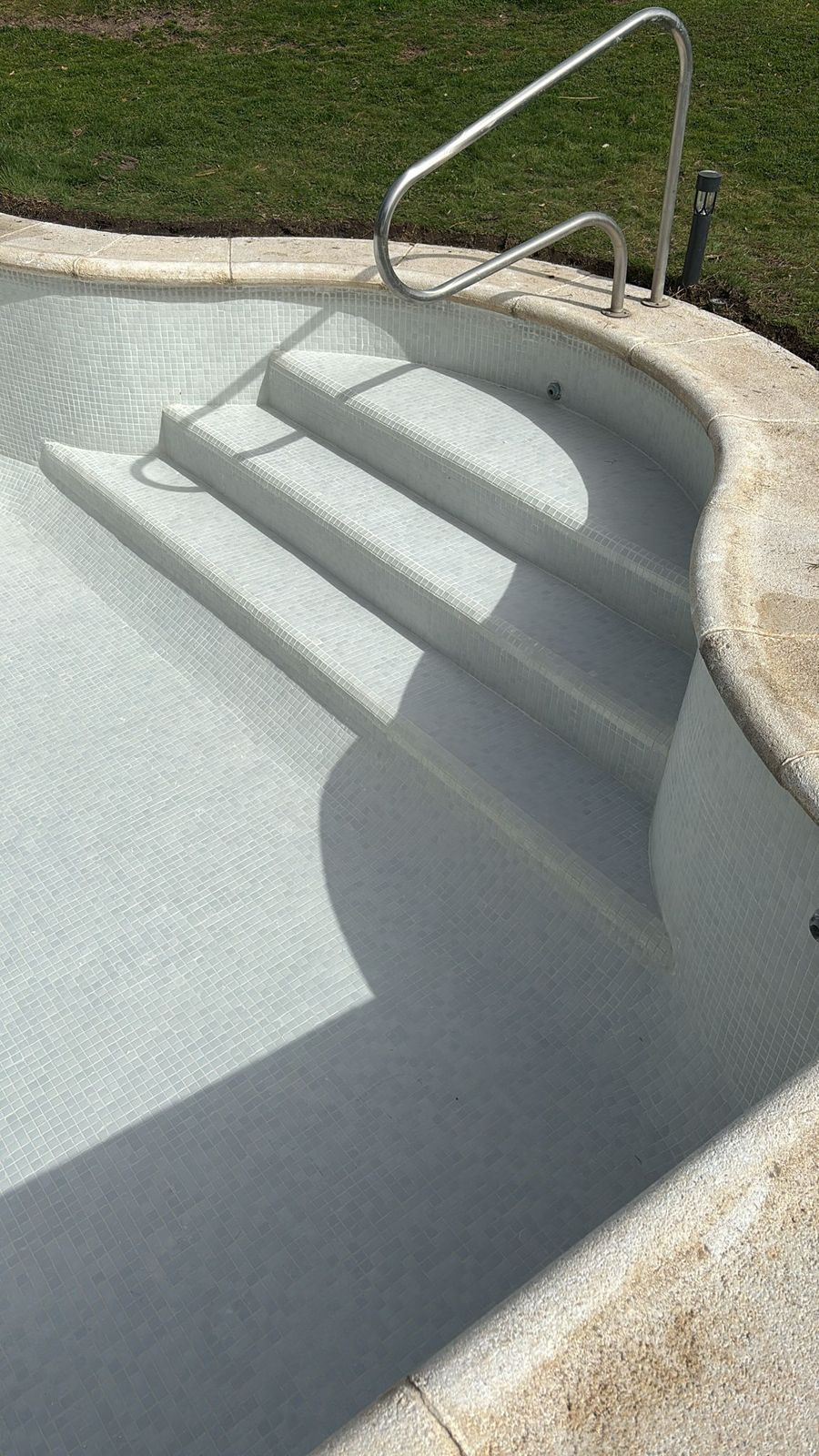 Escalera romana de obra con gresite claro en una piscina terminada