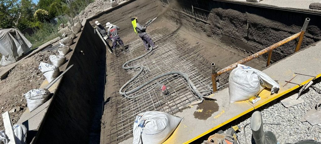 Proyeccion del hormigon a presion sobre el armado de hierro durante el gunitado de una piscina