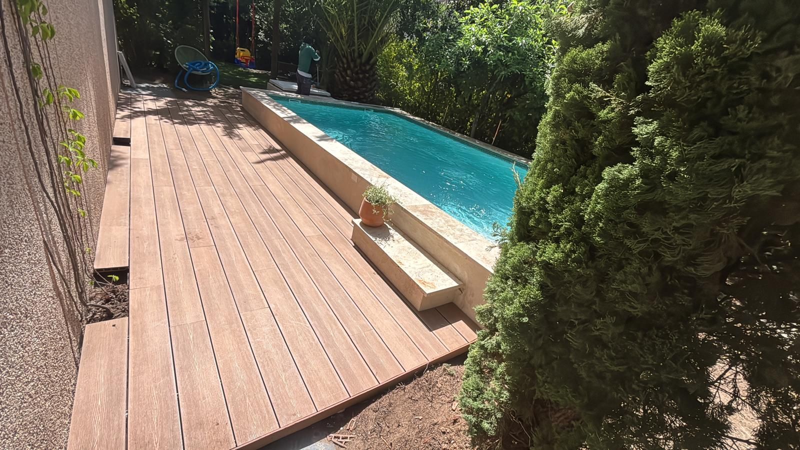 Piscina alargada con tarima de madera alrededor, piscina cuidada con mantenimiento periódico