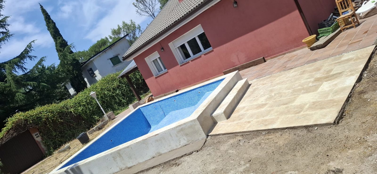Piscina de gresite azul con banco de obra corrido a lo largo de uno de los laterales