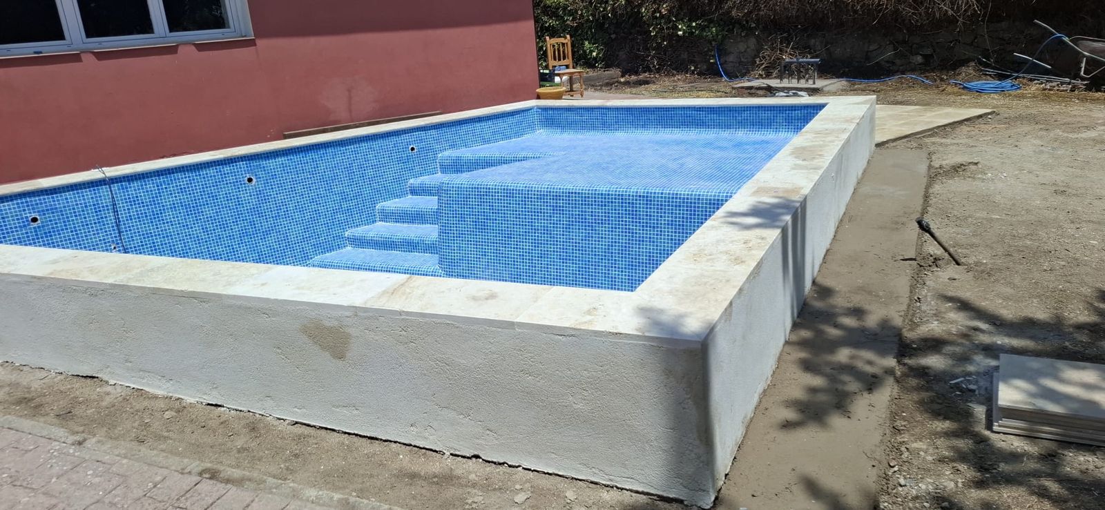 Piscina de obra con gresite azul y escalera romana terminada