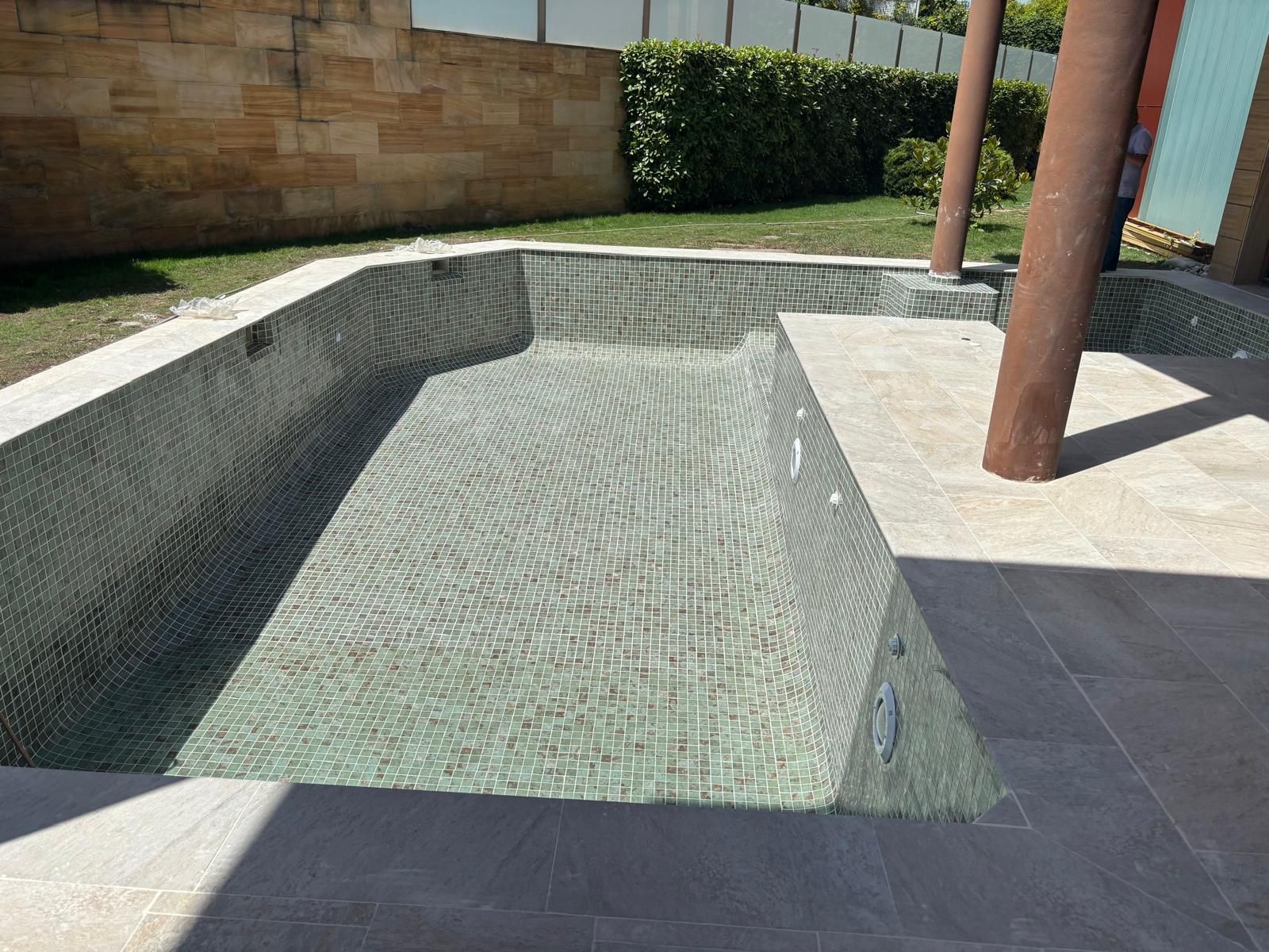 Piscina terminada con gresite verde y coronación de piedra tras reparar los desperfectos