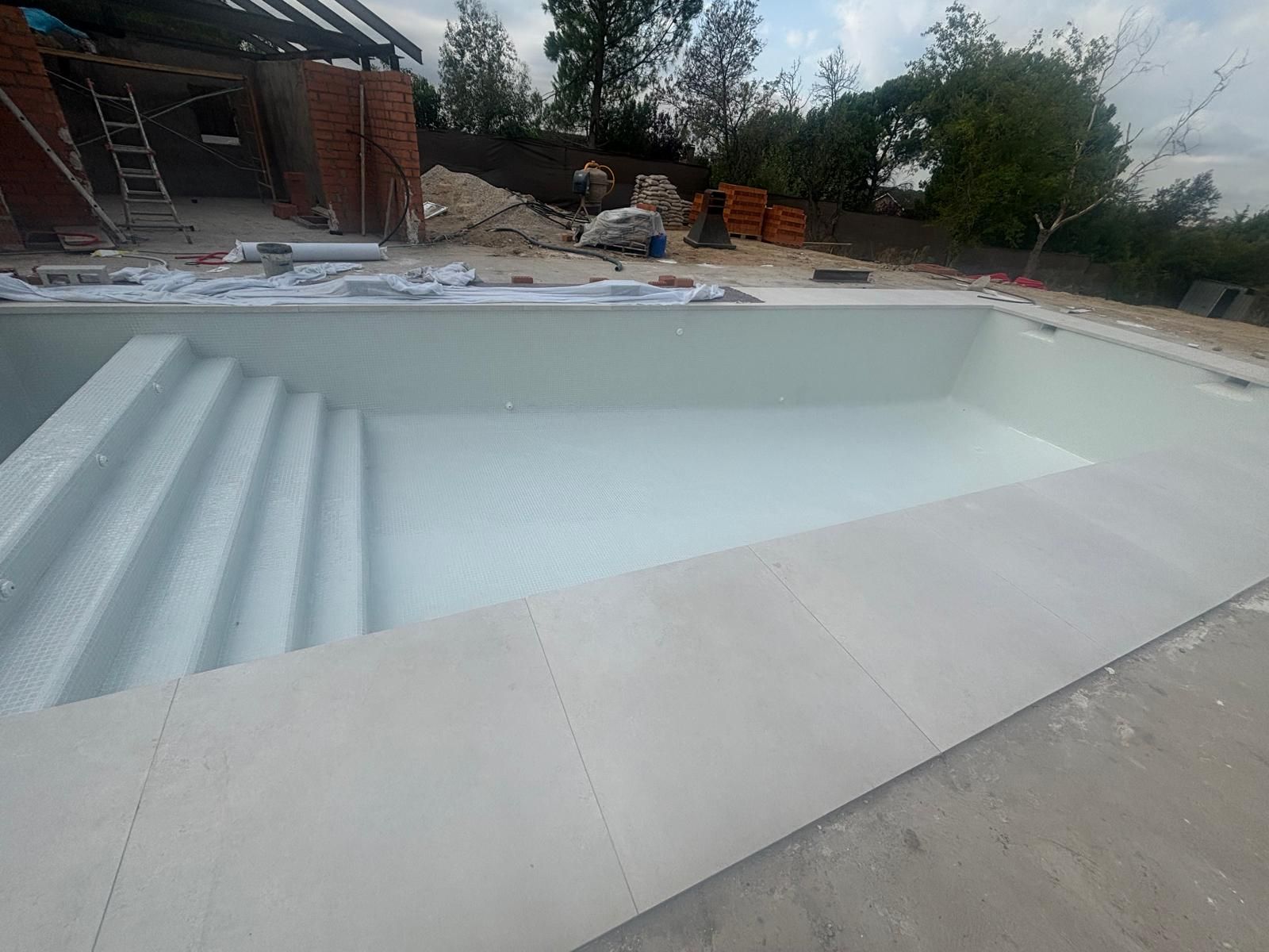 Vaso de piscina de obra recién terminado con los escalones de acceso ya formados en una esquina