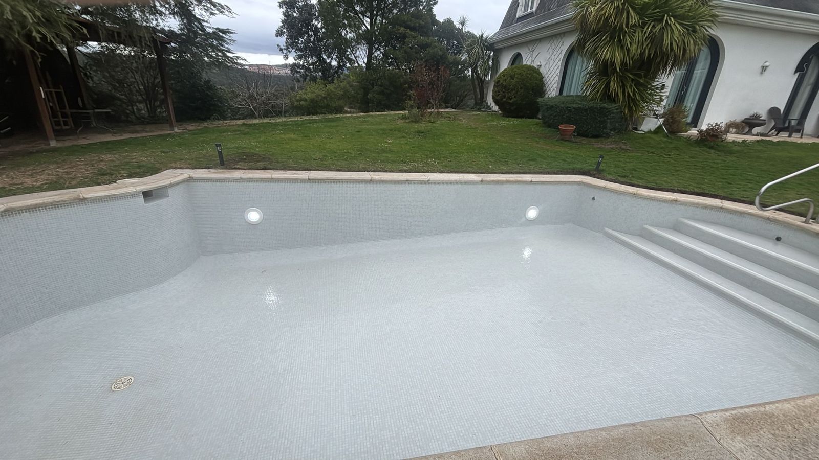 Piscina de obra terminada con revestimiento claro en un chalet de Madrid