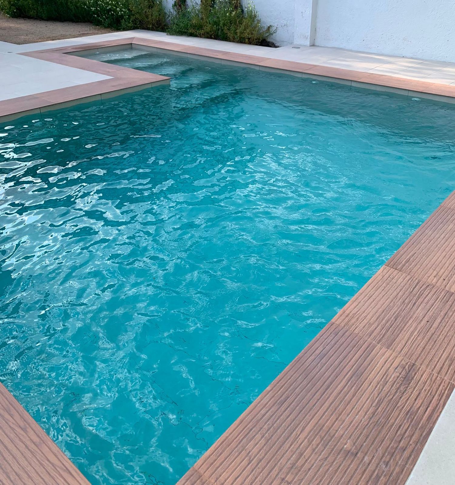 Piscina rectangular terminada y llena, con tarima de madera en uno de los laterales