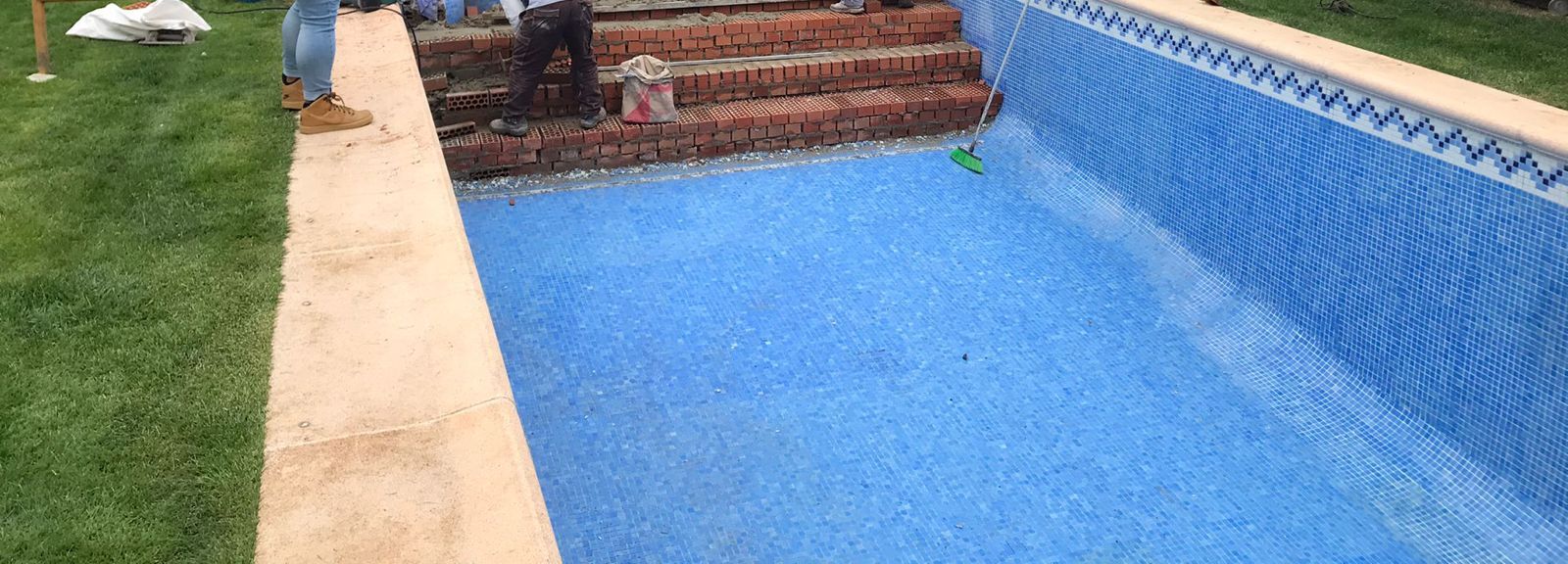 Reparación de un desperfecto de obra en la escalera de una piscina, con el ladrillo visto durante los trabajos