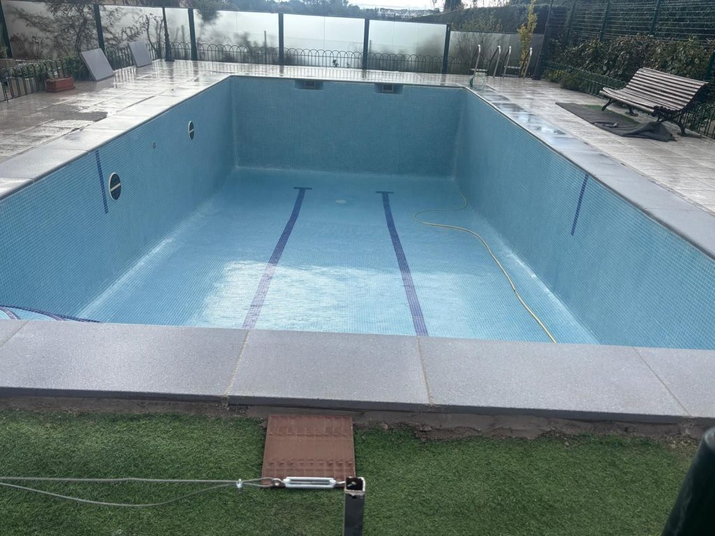 Piscina rectangular de gran tamaño revestida en azul, con la calle de nado marcada en el fondo