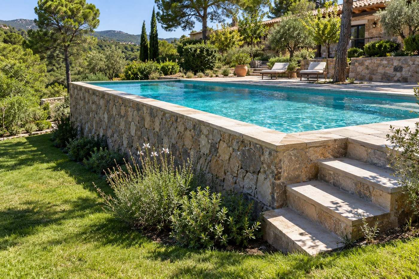 Piscina elevada de obra con muro de piedra natural en una parcela en pendiente